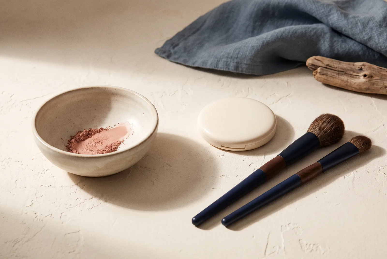 Pinceles de maquillaje y polvos sobre una superficie clara